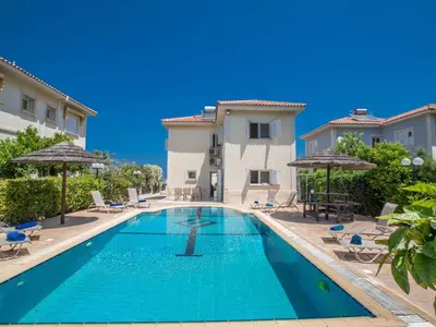a swimming pool with chairs and umbrellas next to a building at Holiday Home in Protaras mit privatem Parkplatz by Interhome in Protaras