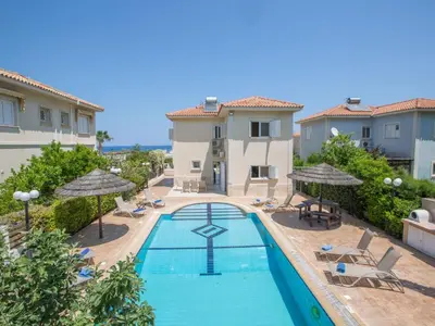 a swimming pool with chairs and umbrellas next to a building at Holiday Home in Protaras mit privatem Parkplatz by Interhome in Protaras