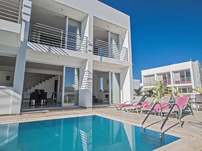 a villa with a swimming pool and pink chairs at Holiday Home Protaras Perle Villa PE15 by Interhome in Protaras