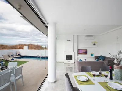 a dining room and living room with a view of a pool at Holiday Home 2-Schlafzimmer-Villa mit Pool- Dachgarten- Meerblick by Interhome in Protaras