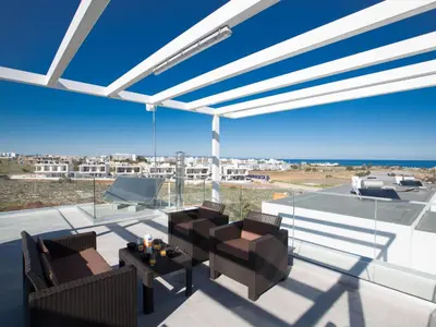 a patio with two chairs and a table on a balcony at Holiday Home Protaras Olivine Villa mit Pool und einem Dachgarten by Interhome in Protaras