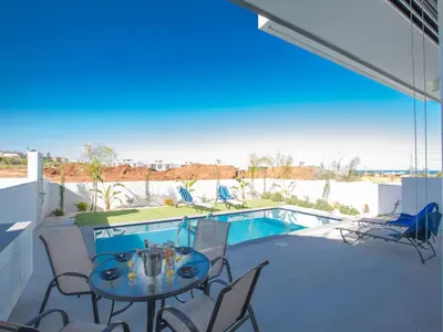 a patio with a table and chairs and a pool at Holiday Home Protaras Olivine Villa mit Pool und einem Dachgarten by Interhome in Protaras