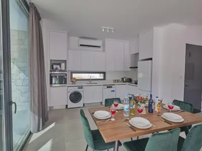a kitchen with a wooden table and green chairs at Holiday Home Protaras Elite Perle Villa EP3C by Interhome in Protaras