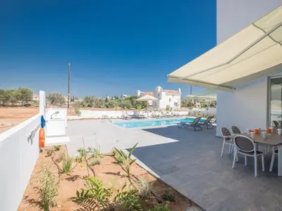 a patio with a table and chairs and a pool at Holiday Home Wunderschöne- geräumige Ferienvilla mit BBQ by Interhome in Protaras