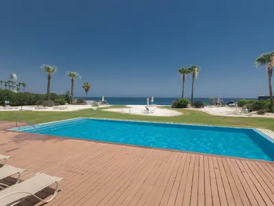 a swimming pool with chairs and the ocean in the background at Apartment Luxuriöse Wohnung am Strand von Thalassa by Interhome in Protaras