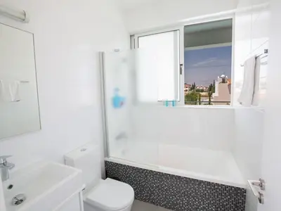 a white bathroom with a toilet and a window at Holiday Home Protaras Greco Villa CCV1 mit beheiztem Pool by Interhome in Protaras