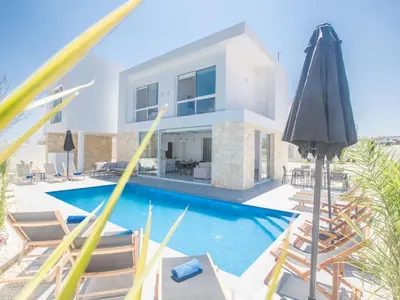 a villa with a swimming pool with chairs and an umbrella at Holiday Home 4-Schlafzimmer-Villa mit Pool im Zentrum von Protaras by Interhome in Protaras