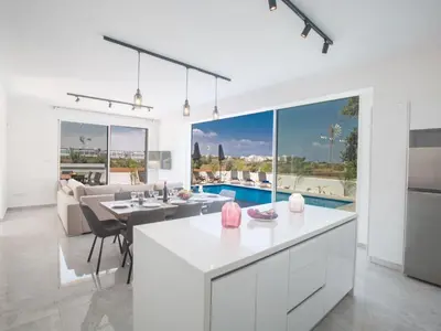 a kitchen and living room with a table and a couch at Holiday Home 4-Schlafzimmer-Villa mit Pool im Zentrum von Protaras by Interhome in Protaras