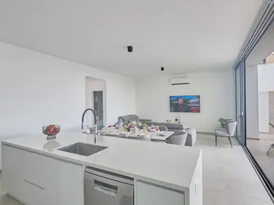 a white kitchen with a sink and a living room at Holiday Home Protaras Aqua Pearl Villa AQ11 im Zentrum by Interhome in Protaras