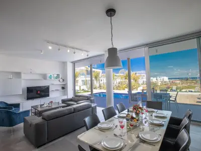 a living room with a dining table and a couch at Holiday Home Schöne Villa Olivine Pearl OL5 mit Garten by Interhome in Protaras