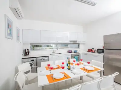a white kitchen with a table and white chairs at Holiday Home Neue Ferienvilla für 10 Personen by Interhome in Protaras