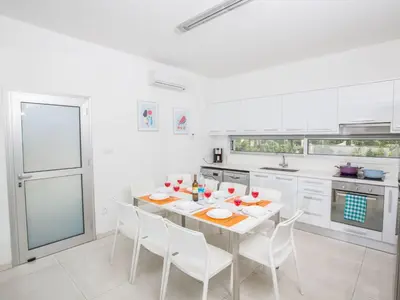 a white kitchen with a table and white chairs at Holiday Home Neue Ferienvilla für 10 Personen by Interhome in Protaras