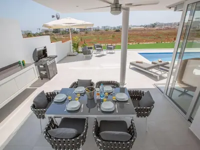 a patio with a table and chairs and a pool at Holiday Home Haus in Pernera mit Bi-Fold Patio by Interhome in Protaras