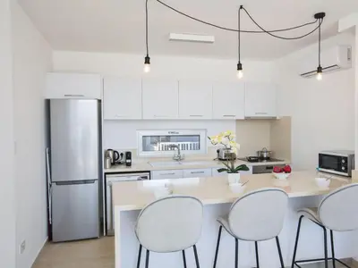 a kitchen with white cabinets and a table and chairs at Holiday Home 3-Schlafzimmer-Villa mit privatem Pool im Zentrum by Interhome in Protaras