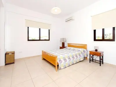 a white bedroom with a bed and a table at Holiday Home Protaras Ferienvilla AV6 by Interhome in Protaras