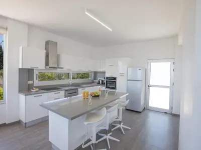 a kitchen with white appliances and a large island with stools at Holiday Home Ferienvilla Chloe mit Terrasse und Garten by Interhome in Protaras