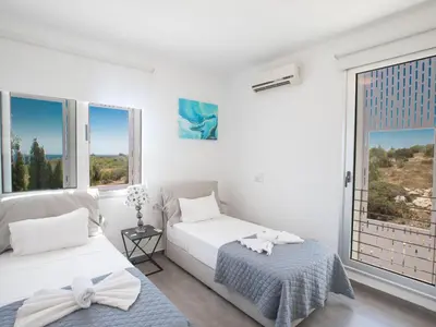 a white bedroom with two beds and a window at Holiday Home Ferienvilla Chloe mit Terrasse und Garten by Interhome in Protaras