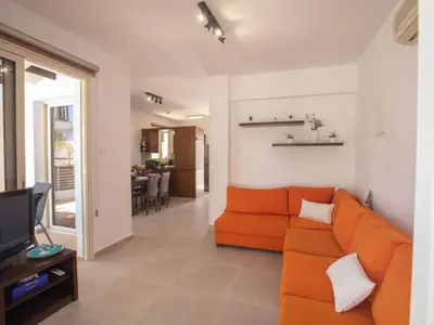a living room with an orange couch and a television at Holiday Home Protaras Menelaos Villa MV7 by Interhome in Paralimni