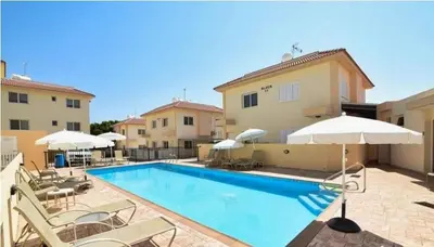 a swimming pool with chairs and umbrellas next to a building at Penthouse Apartment - Sleeps 4 - Sea Views in Paralimni