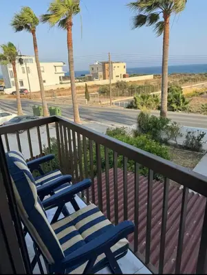 two blue chairs on a balcony with palm trees at Sea view maisonette on coastal road, Zygi in Zygi