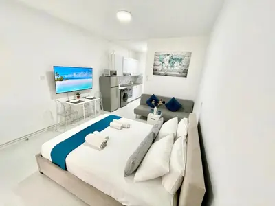 a white bedroom with a large bed and a couch at Silver Blu APT - Beachside - Location - Office in Limassol
