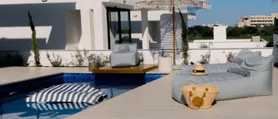 a patio with two beds and a swimming pool at Nesea Seaside Luxury Escape in Paralimni