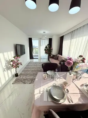 a white living room with a table and a couch at Brand new 2 bedrooms apartment in Grand Sapphire in İskele