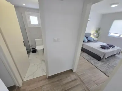 a white bedroom with a bed and a bathroom at 1 bedroom, Agia Napa 1 - C in Ayia Napa