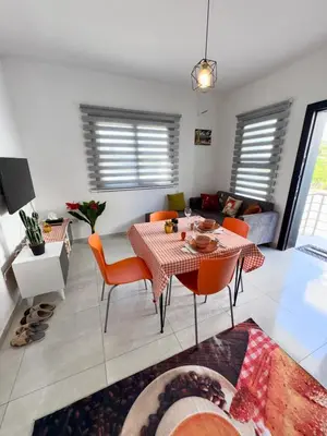 a living room with a table and chairs and a couch at Orange Sunset Duplex Lapta 2 bedrooms close to Merit Casino in Meniko