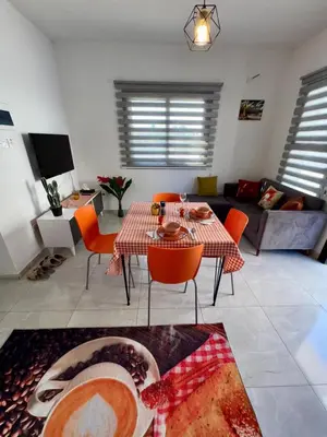 a living room with a table and orange chairs at Orange Sunset Duplex Lapta 2 bedrooms close to Merit Casino in Meniko
