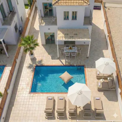 an overhead view of a swimming pool with chairs and umbrellas at Fig Tree Beach Villa One in Protaras