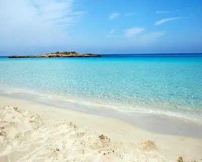 a sandy beach with an island in the ocean at Fig Tree Beach Villa One in Protaras