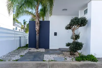 a white building with two palm trees in front of it at White Pearl Villa Protaras 7 in Paralimni
