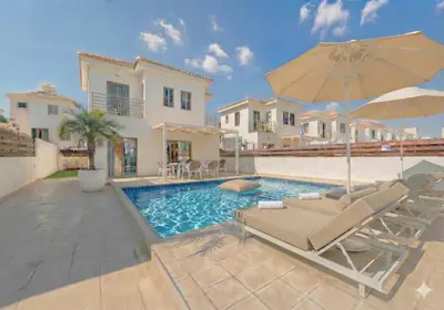 a swimming pool with two lounge chairs and an umbrella at Fig Tree Beach Villa Six in Protaras