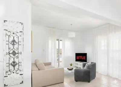a white living room with a couch and a chair at Fig Tree Beach Villa Six in Protaras