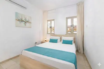a bedroom with a large white bed with blue pillows at Fig Tree Beach Villa Six in Protaras