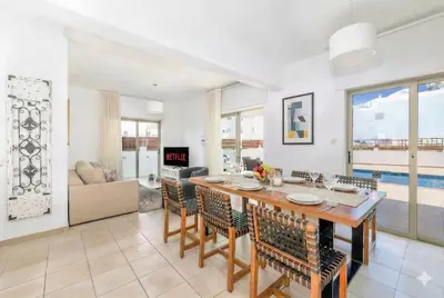 a dining room and living room with a table and chairs at Fig Tree Beach Villa Six in Protaras
