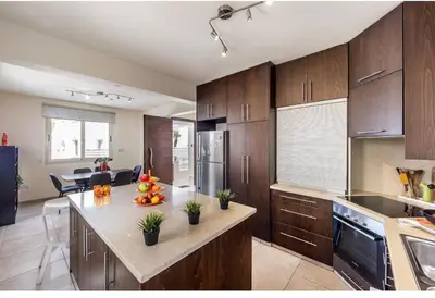 a kitchen with wooden cabinets and a counter top at Daffodil villa in Pernera in Protaras