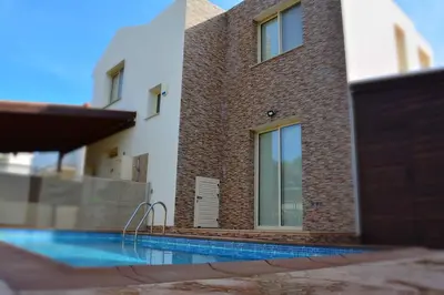 a house with a swimming pool next to a building at Daffodil villa in Pernera in Protaras