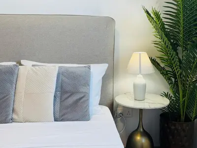 a bed with blue and white pillows and a lamp at Makenzie View Penthouse in Larnaka