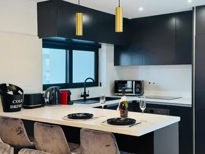 a kitchen with black cabinets and a counter with wine glasses at Makenzie View Penthouse in Larnaka