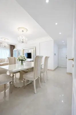 a white dining room with a white table and chairs at Gulf Beach Apartment by TrulyCyprus in Limassol