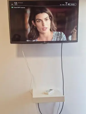 a television hanging on a wall with a remote control at Olive studio in Limassol