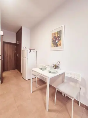 a white table and chairs in a kitchen with a refrigerator at Olive studio in Limassol
