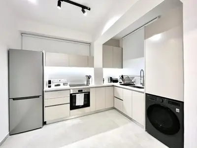 a kitchen with white cabinets and a washer and dryer at STAY Aelia Apartment in Nicosia