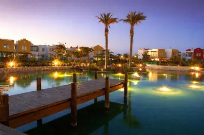 a dock in the water with palm trees and buildings at Modern Seaside Apartment Steps to the Beach in Pervolia