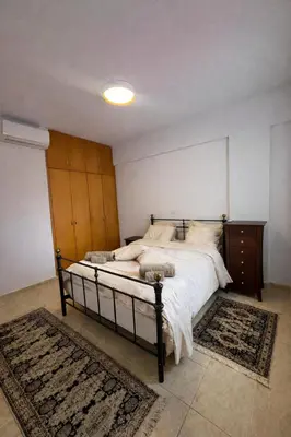 a bedroom with a large bed with a wooden headboard at Modern Seaside Apartment Steps to the Beach in Pervolia