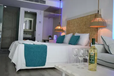 a bedroom with a bed with wine glasses and a couch at Seaside Stay Room in Ayia Napa