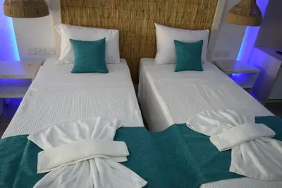 two beds with green and white sheets and pillows at Seaside Stay Room in Ayia Napa