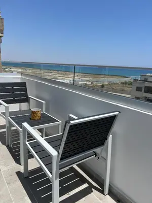 two benches and a table on a balcony looking out at the ocean at Sea view Appartment in Larnaka